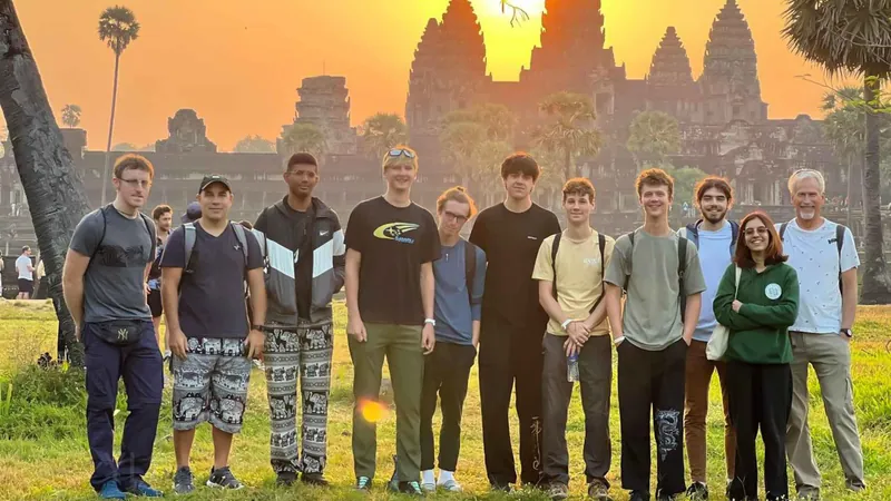 A tour group posing on the lawn in front of the Angkor Wat towers at sunrise on a two-day Angkor Wat tour