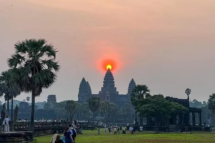 The sun rising behind the central tower of Angkor Wat with palms on either side on a private Angkor Wat sunrise tour