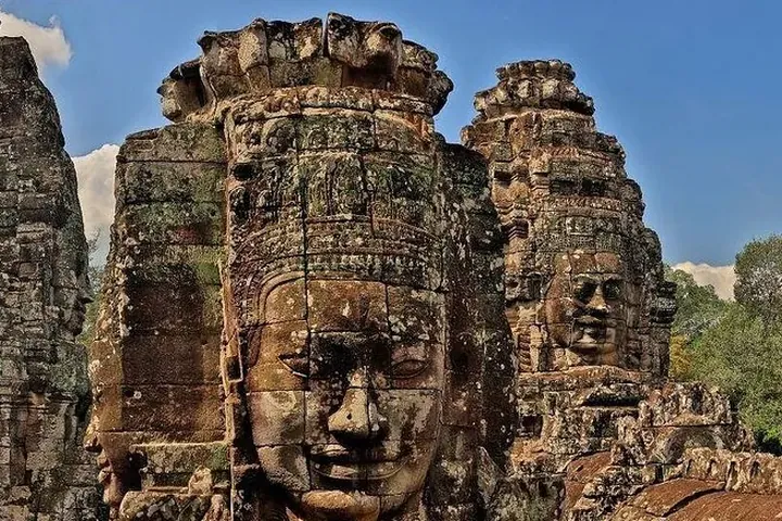 The carved stone faces of the Bayon towers under a blue sky on a private Angkor Wat sunrise tour